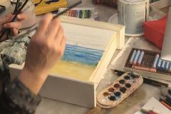 Momento della realizzazione di un mobiletto in legno, dipinto con tecnica mista